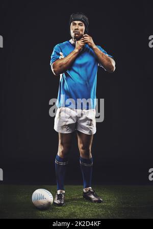 Ich fühle mich noch eingeschüchtert. Studioaufnahme eines jungen Rugby-Spielers auf dem Spielfeld in voller Länge. Stockfoto