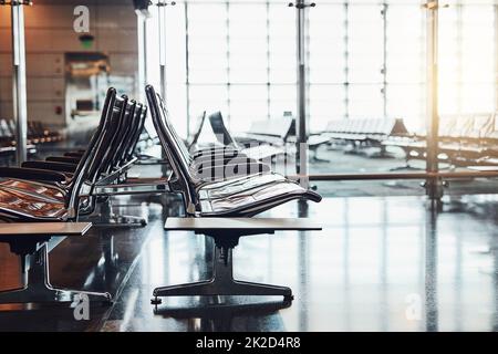 Wo Menschen unterschiedliche Orte bilden, kommen zusammen. Aufnahme von Sitzreihen in einer leeren Abflughalle des Flughafens. Stockfoto