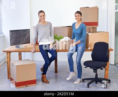 Bereit für neue Anfänge. Aufnahme zweier Unternehmerinnen, die in ein neues Büro ziehen. Stockfoto