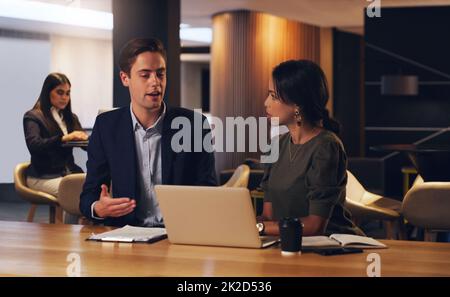 Setzen Sie in die harte Arbeit, um erfolgreich zu sein groß. Aufnahme von zwei Geschäftsleuten, die nachts in einem Büro an einem Laptop arbeiten. Stockfoto