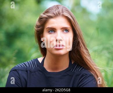 Schönheit im Freien. Eine wunderschöne junge Frau, die nachdenklich im Freien wegschaut. Stockfoto