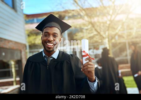 Meine Erfolgsgeschichte beginnt hier. Porträt eines glücklichen jungen Mannes, der am Abschlusstag ein Diplom hält. Stockfoto