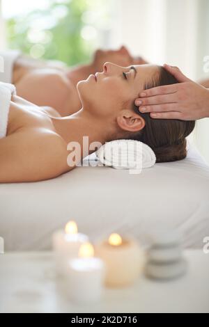 Genießen Sie einen Tag der Verwöhnung. Ein Mann und eine Frau liegen zusammen auf Massageliegen und erhalten Kopfmassagen. Stockfoto