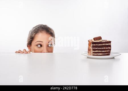 Shes ein Liebhaber von Schokolade. Studioaufnahme einer attraktiven jungen Frau, die von etwas Süßem verlockt wird. Stockfoto