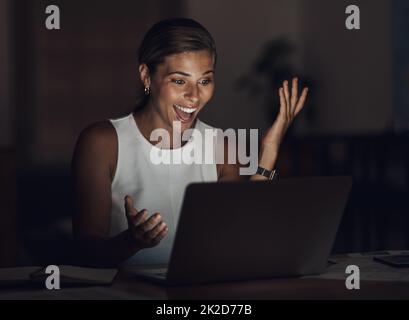 Ihre Zeit war jeden Cent wert. Aufnahme einer jungen Geschäftsfrau, die einen Laptop benutzt und während eines späten Abends bei der Arbeit überrascht aussucht. Stockfoto