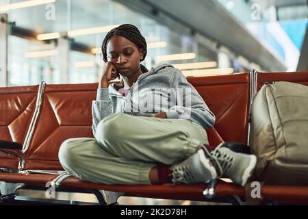 Reisen kann anstrengend sein. Aufnahme einer jungen Frau, die am Flughafen einschläft, während sie auf den Abflug wartet. Stockfoto