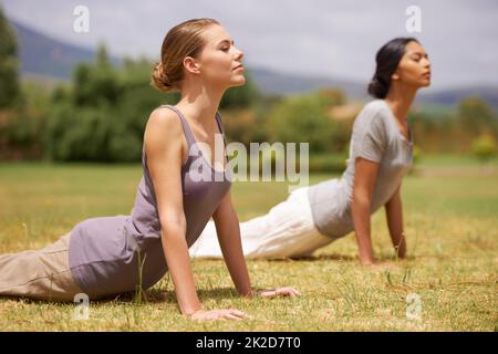 Sich um Körper und Geist kümmern. Frauen machen Yoga im Freien. Stockfoto