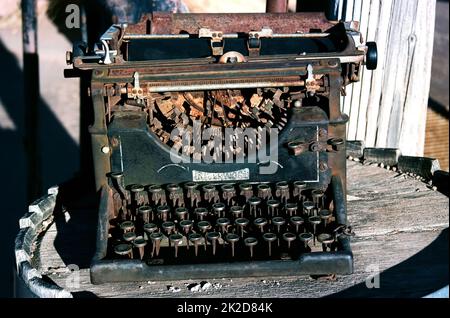 Antike rostige Schreibmaschine auf einem Holzfass Stockfoto