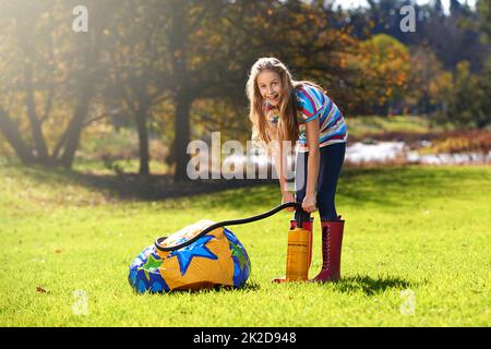 Schulen und der Sommer ist da. Porträt eines Teenagers, das einen aufblasbaren Ball im Freien aufbläst. Stockfoto