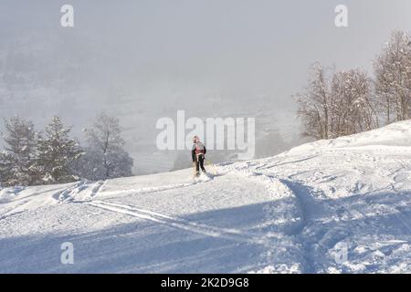 Eine Frau mit schwarzer Skikleidung, die in norwegen einen Berg hinunterfährt Stockfoto