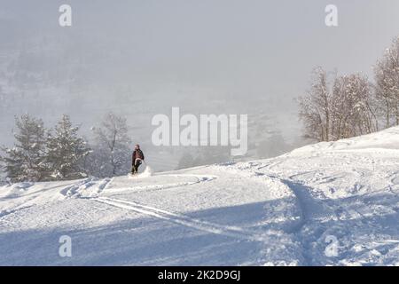 Eine Frau mit schwarzer Skikleidung, die in norwegen einen Berg hinunterfährt Stockfoto