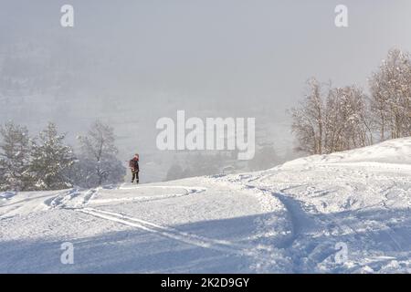 Eine Frau mit schwarzer Skikleidung, die in norwegen einen Berg hinunterfährt Stockfoto