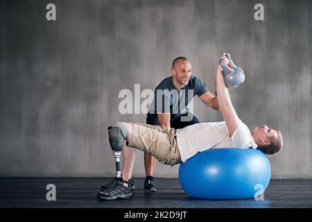 Sie können es tun. Ein Physiotherapeut Ausbildung mit einem Patienten. Stockfoto