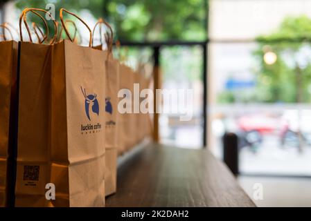 Lieferung von Papiertüten auf einem Holztisch im Luckin Coffee Shop Stockfoto