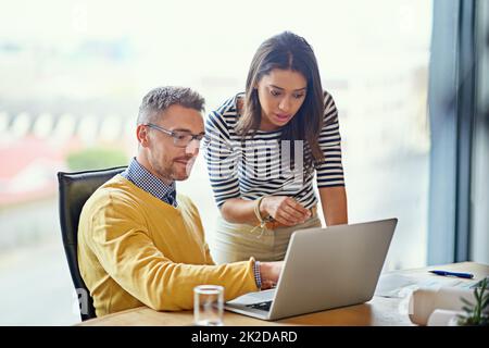 Sie sind auf mehr als eine Weise miteinander verbunden. Aufnahme von Kollegen, die in einem Büro an einem Laptop arbeiten. Stockfoto