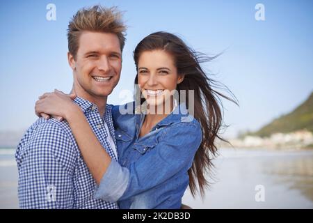 Unsere Liebe ist für immer. Ein junges Paar, das sich glücklich am Strand umarmt. Stockfoto