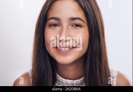 Lächle einfach. Beschnittenes Porträt eines attraktiven Teenagers, das allein vor weißem Hintergrund im Studio steht. Stockfoto