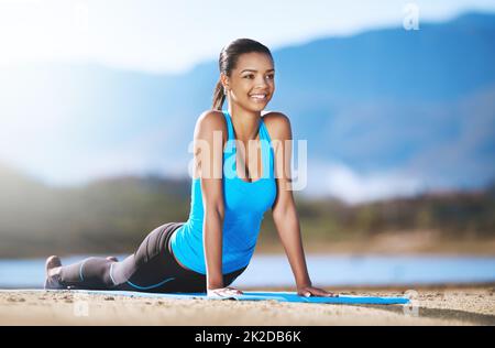 Nehmen Sie sich Zeit, um zu tun, was Ihre Seele glücklich macht. Aufnahme einer jungen Frau, die im Freien Yoga praktiziert. Stockfoto