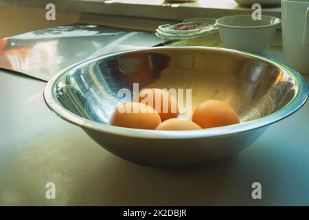 Hühnereier in einer Aluminiumschüssel auf der Arbeitsplatte Stockfoto