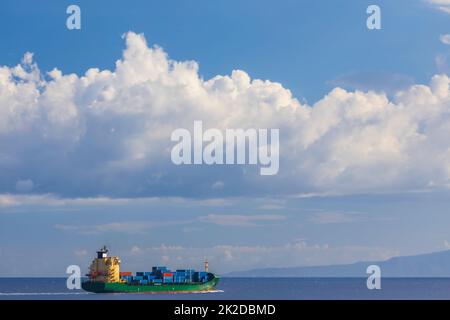 Frachtschiff in der Nähe Capo Peloro Leuchtturm in Punta del Faro an der Straße von Messina, nordöstlichste Landzunge von Sizilien, Italien Stockfoto