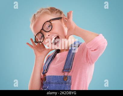 Diese Brille lässt mich niedlich fühlen. Studioaufnahme eines kleinen Mädchens mit einer Hipster-Brille auf blauem Hintergrund. Stockfoto