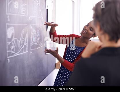 Das ist also mein erster Entwurf Aufnahme von zwei Designerinnen, die in ihrem Büro an einer Tafel arbeiten. Stockfoto