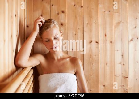 Das ist ihre Glückseligkeit. Eine wunderschöne blonde Frau, die sich in der Sauna entspannt. Stockfoto