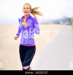 Ich bin für diesen Lauf gepumpt. Porträt einer jungen Frau beim Joggen am Strand. Stockfoto