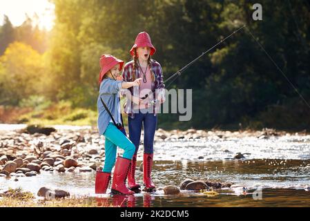 Wir haben eins. Aufnahme von zwei jungen Mädchen, die an einem Fluss fischen. Stockfoto