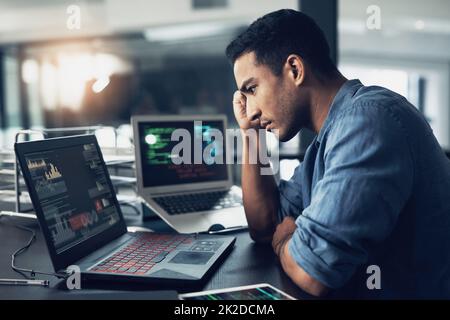 Ein Spiel ohne Reset am Ende. Aufnahme eines jungen Mannes, der unter Kopfschmerzen leidet, während er in einem modernen Büro einen Laptop benutzt. Stockfoto