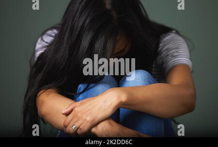 Manchmal willst du nur deinen Kopf begraben. Zugeschnittene Aufnahme einer nicht erkennbaren jungen Frau, die vor grünem Hintergrund im Studio deprimiert aussieht. Stockfoto