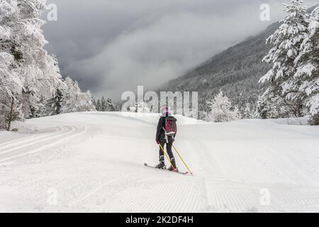 Frau mit Skikleidung, Helm und Rucksack Skifahren Stockfoto