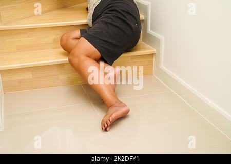 Asiatische Dame Frau Verletzungen durch Herunterfallen auf rutschigen Oberflächen Treppen zu Hause. Stockfoto