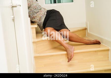 Asiatische Dame Frau Verletzungen durch Herunterfallen auf rutschigen Oberflächen Treppen zu Hause. Stockfoto