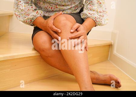 Asiatische Dame Frau Verletzungen durch Herunterfallen auf rutschigen Oberflächen Treppen zu Hause. Stockfoto