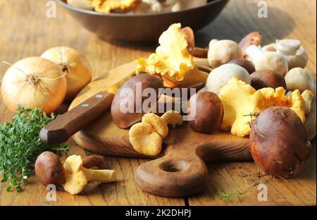 Mischung von Waldpilzen auf Schneidebrett über alten Holztisch Stockfoto