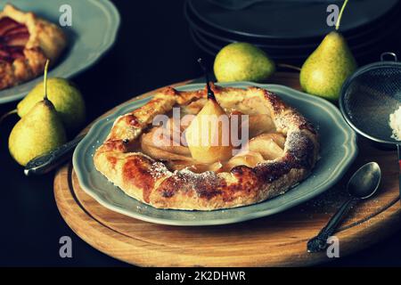 Hausgemachte Galette mit Birnen auf dunklem Hintergrund. Süßer offener Obstkuchen. Herbstbäckerei. Draufsicht Stockfoto