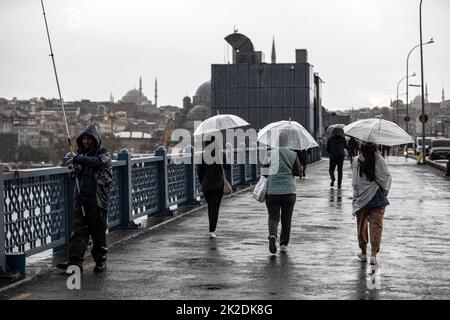 Istanbul, Türkei. 22. September 2022. Menschen mit Sonnenschirmen, die bei Regen auf der Galata-Brücke spazieren gehen. Der starke Regen, der in Istanbul wirksam war, hat das Leben um die Galata-Brücke und den Karakoy-Dock negativ beeinflusst. Kredit: SOPA Images Limited/Alamy Live Nachrichten Stockfoto