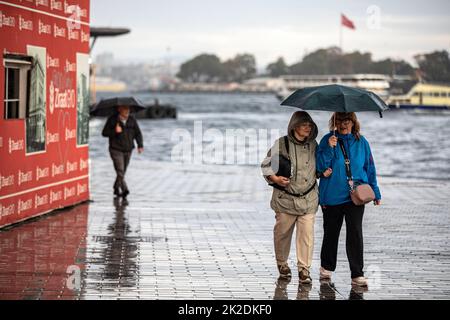 Istanbul, Türkei. 22. September 2022. Die Menschen sahen, wie sie bei einem Regen mit Sonnenschirmen um den Karakoy Kai wanderten. Der starke Regen, der in Istanbul wirksam war, hat das Leben um die Galata-Brücke und den Karakoy-Dock negativ beeinflusst. (Foto von Onur Dogman/SOPA Images/Sipa USA) Quelle: SIPA USA/Alamy Live News Stockfoto