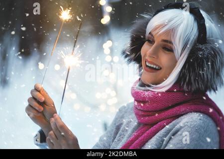 Junge glückliche Frau mit Wunderkerzen im winterverschneiten Wald Stockfoto