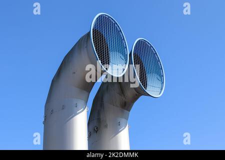 Zwei große Schornsteine mit Gittern davor, die von unten genommen wurden. Stockfoto