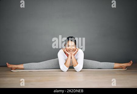 Yoga ist der beste Weg, um den Tag zu beginnen. Porträt einer attraktiven jungen Frau, die die Splits in ihrer Yoga-Routine macht. Stockfoto