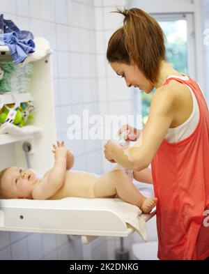 Babysitting kann eine chaotische Arbeit sein. Niedlich junge Mutter Wechsel ein babys Windel. Stockfoto