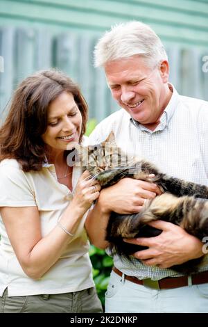 Hes wie ein Mitglied der Familie. Ausgeschnittene Aufnahme eines älteren Paares mit ihrer Katze im Freien. Stockfoto