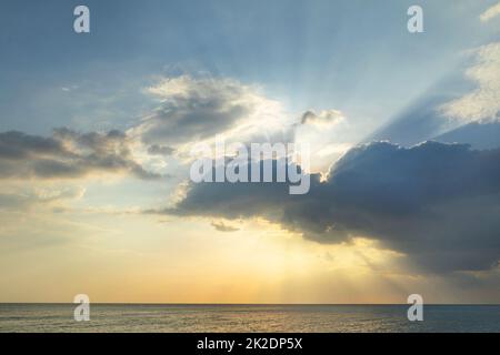 Wunderschöne Sonne, die durch Wolken über dem Meer scheint Stockfoto