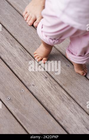 Die ersten Schritte Beschnittenes Nahaufnahme-Bild einer Mutter, die ihrem Baby hilft, ihre ersten Schritte zu machen. Stockfoto