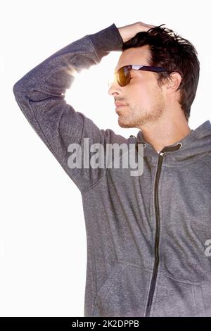 Sommerlich cool. Aufnahme eines hübschen jungen Mannes, der eine Sonnenbrille trägt und seine Hand durch die Haare läuft. Stockfoto