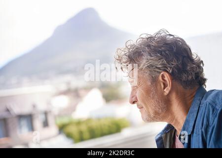 Ein Blick zum entkommen. Ein reifer Mann, der nachdenklich aus dem Fenster schaut. Stockfoto