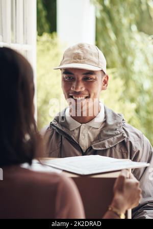 Holen Sie sich Ihren Service mit einem Lächeln. Aufnahme eines jungen Mannes, der einem Kunden zu Hause ein Paket liefert. Stockfoto