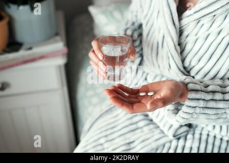 Ich hoffe, dass ich mich dadurch besser fühle. Ein kurzer Schuss einer unkenntlichen Frau, die ihre Medikamente zu Hause in ihrem Schlafzimmer einnahm. Stockfoto